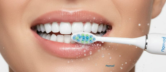 Gros plan d'un brossage de dents avec une brosse à dent sonique blanche Nomad Boutique, illustrant les questions essentielles : Quand, Où, Quoi, Qui, Pourquoi et Comment.