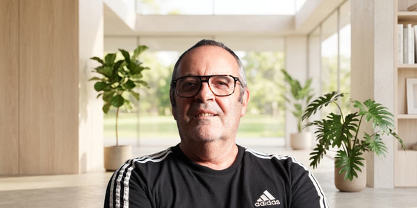 Photographie portrait du fondateur de Nomad, un homme mûr avec des lunettes et une barbe légère, portant un t-shirt Adidas noir à bandes blanches.
